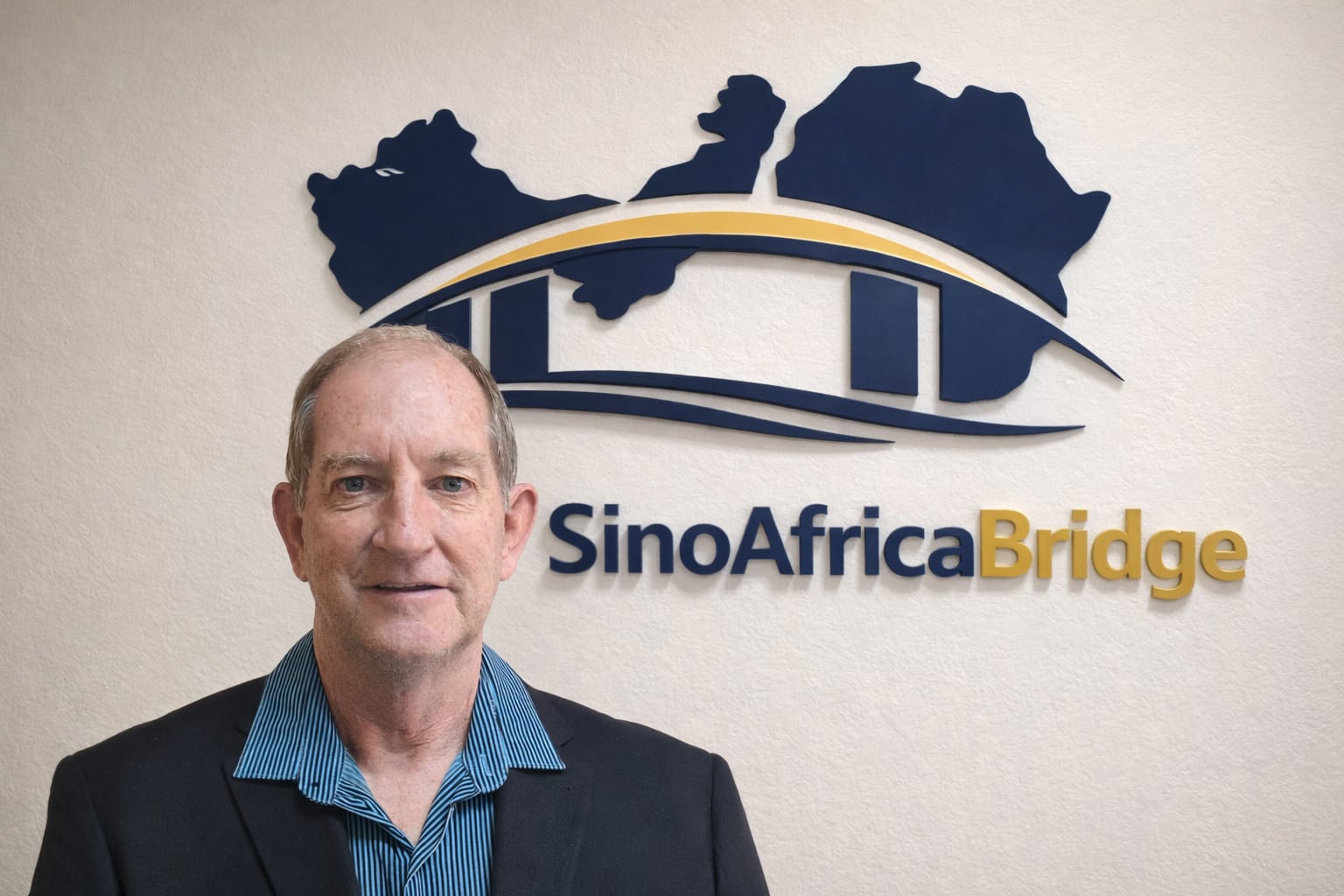 Chris Peo, founder of Sino Africa Bridge, in front of the company signage